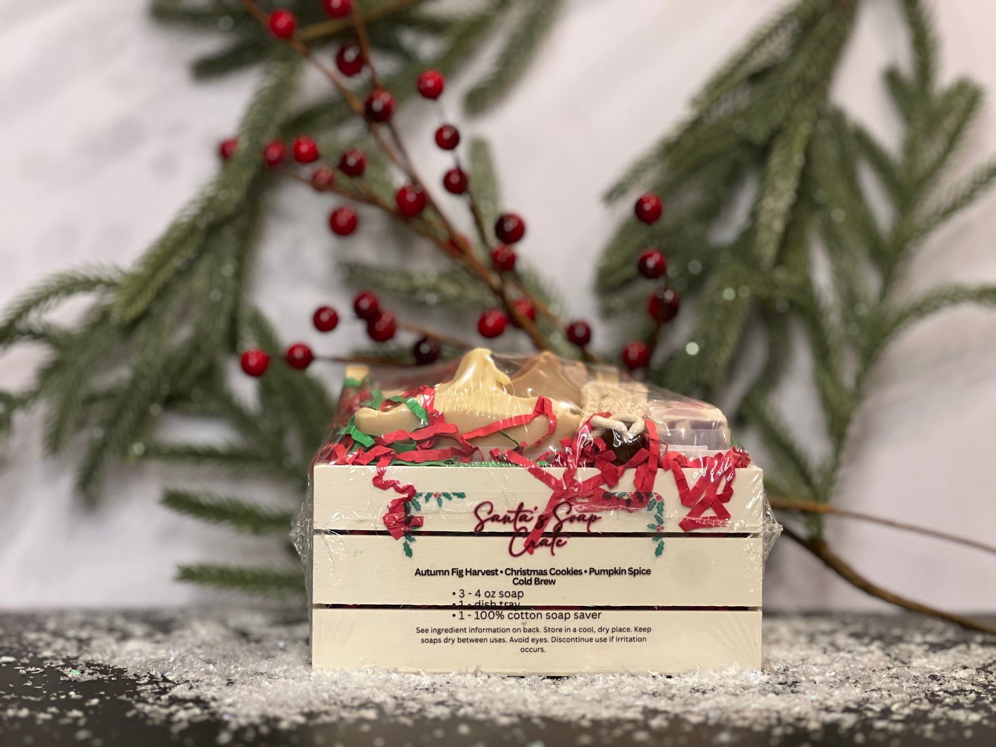 Soap in a small crate with Fall and Christmas designs and scents, with a white background, berries, tree foliage and snow decorations. 