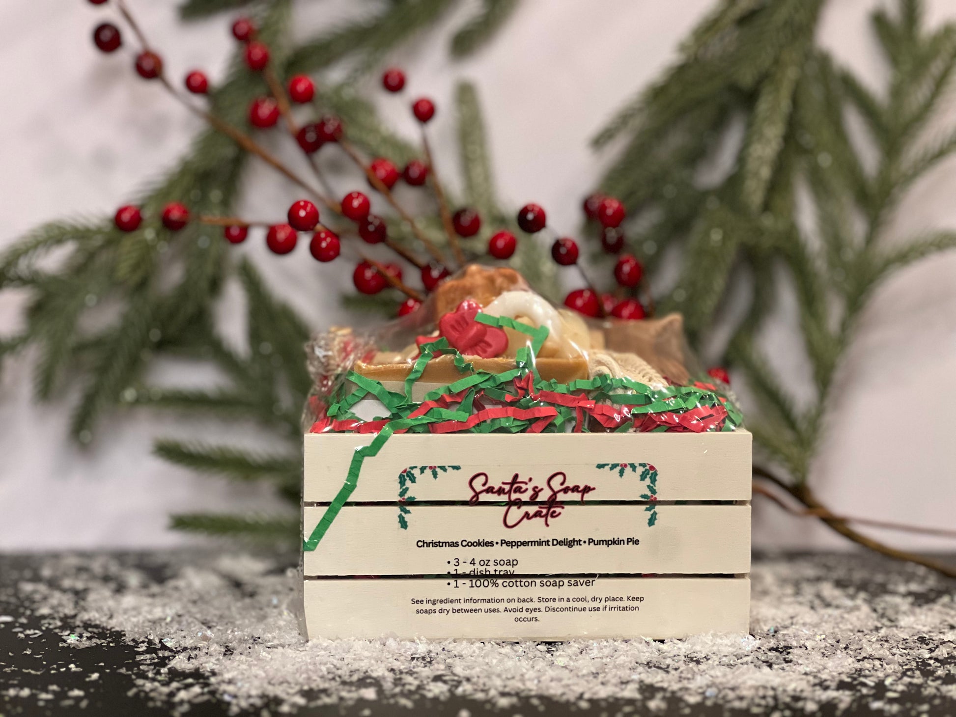 Soap in a small crate with Fall and Christmas designs and scents, with a white background, berries, tree foliage and snow decorations. 